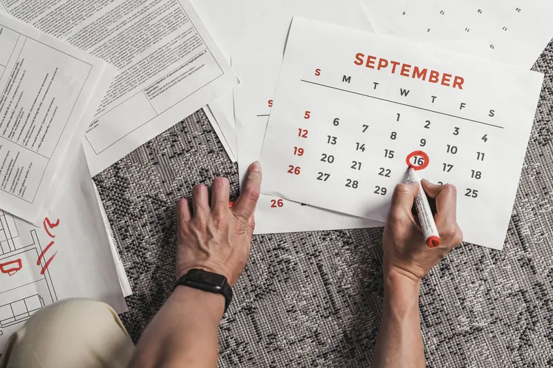 Person prüft Unterlagen und Kalender an einem Schreibtisch